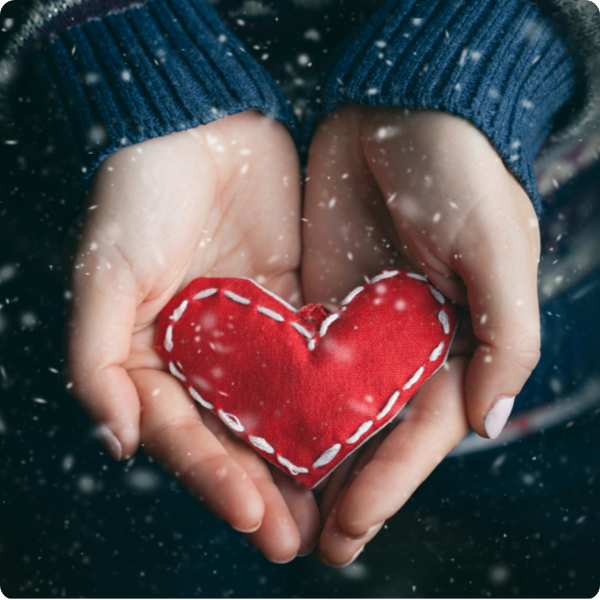 A pair of hands holding a plush heart.