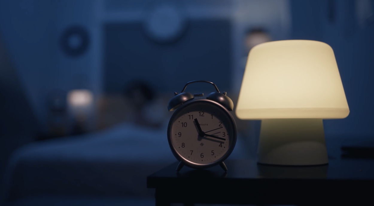 An alarm clock beside a glowing lamp in Tarde