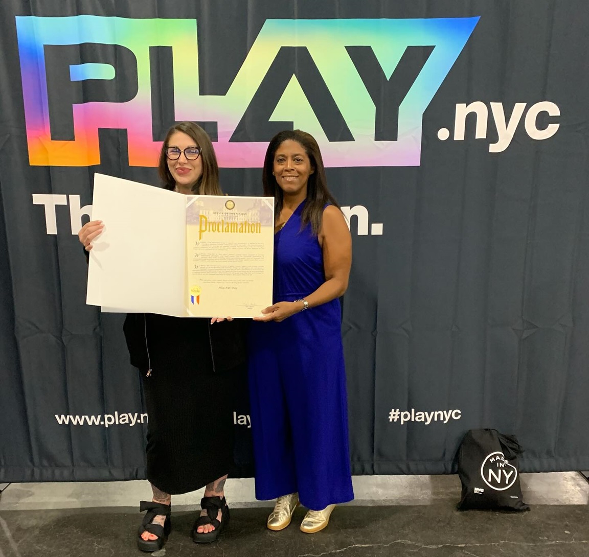 MOME’s Alia Jones-Harvey presents Play.NYC executive director Krysti Pryde with a 10th anniversary proclamation 