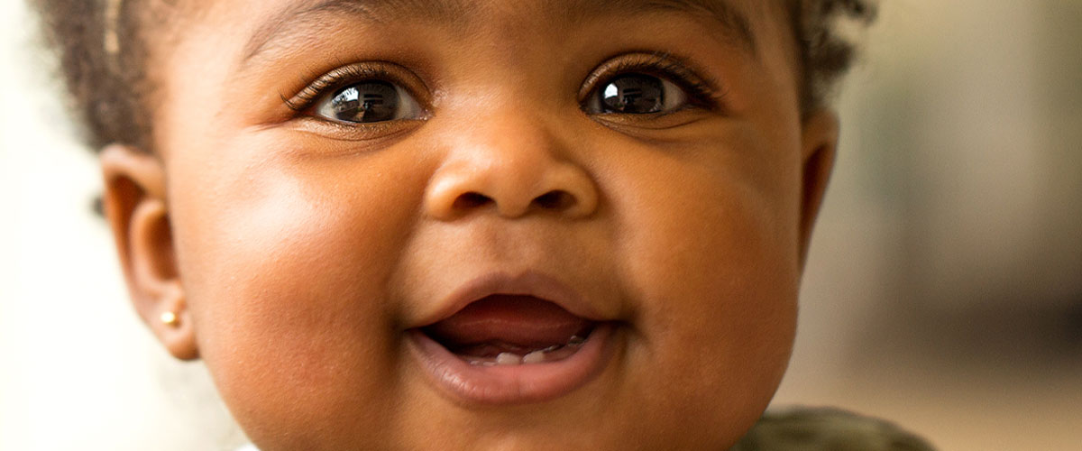 Baby smiling with two teeth showing.