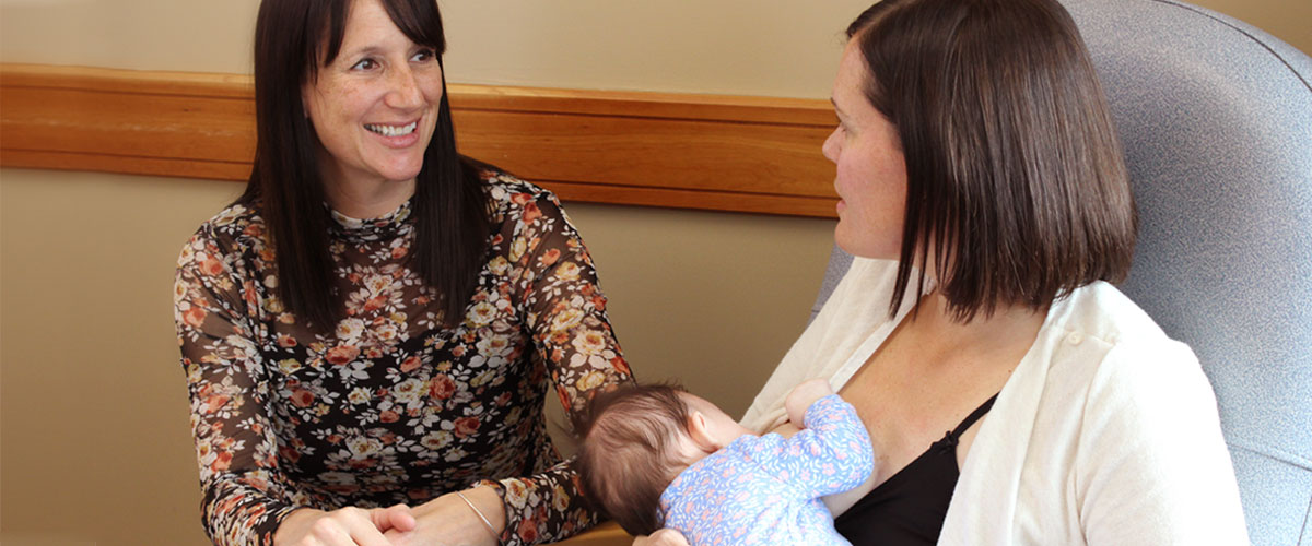 Two adults, one is breastfeeding a baby