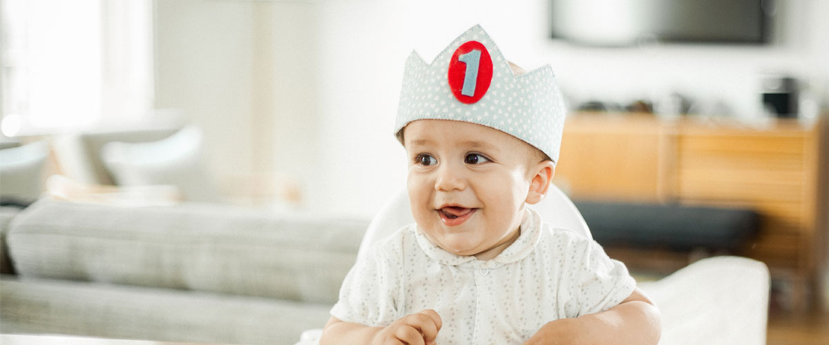 Baby wearing birthday hat with number one on it.