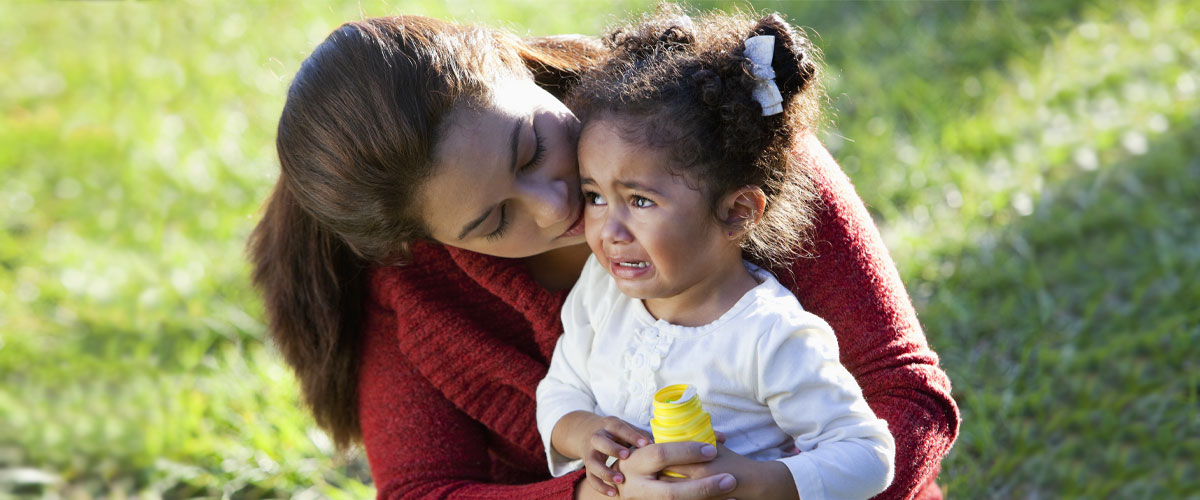 Adult holding crying toddler.