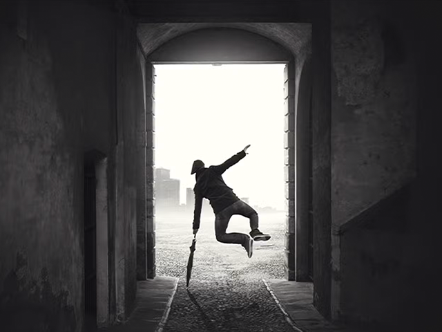 An image of a man dancing in an alley with an umbrella.
