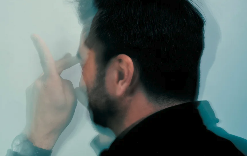 A blurry photo of a man with his fingers flexed in front of his face.