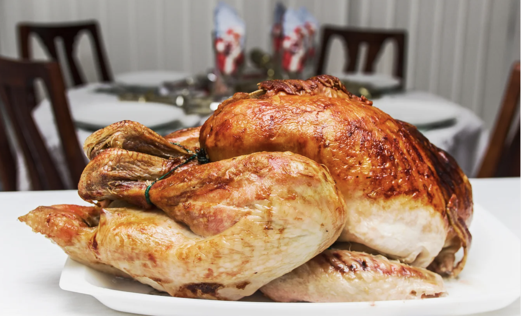 A golden brown cooked turkey sits on a white platter