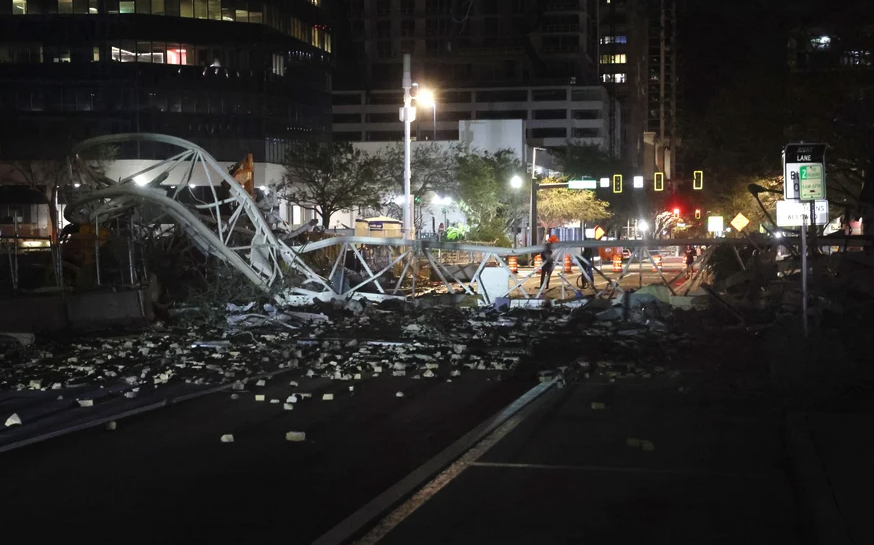 A crane is collapsed across a road, with debris scattered everywhere
