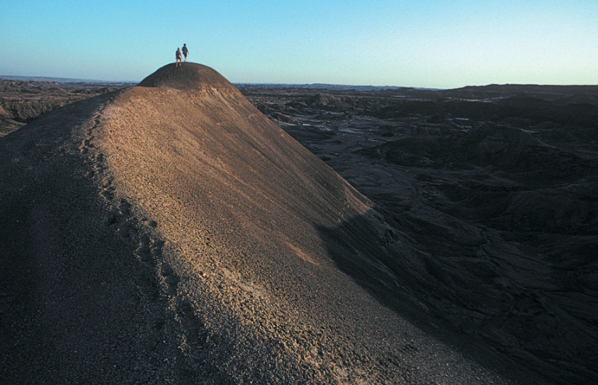 Two researchers walk along the crest of a rugged hillside in the Afar region of Ethiopia