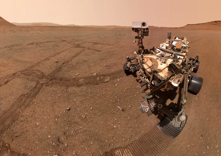 A selfie of NASA's Perseverance Mars rover with sample tubes it deposited at a sample depot it is creating within an area of Jezero Crater nicknamed "Three Forks." The ninth tube dropped during the construction of the depot, containing the sample the science team refers to as "Atsah, " can be seen in front of the rover. Other sample tubes are visible in the background.