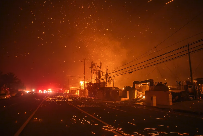 Palisades Fire burns homes along a highway, and the wind burns orange embers toward the photoagrapher