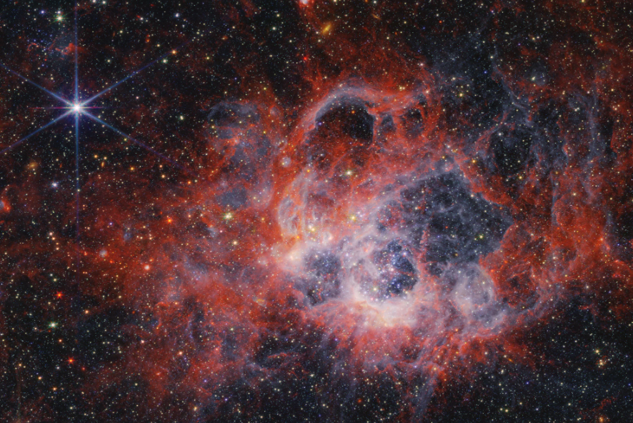 An image of a red, orange, white, and blue nebula, with a shining solitary blue star in the upper left
