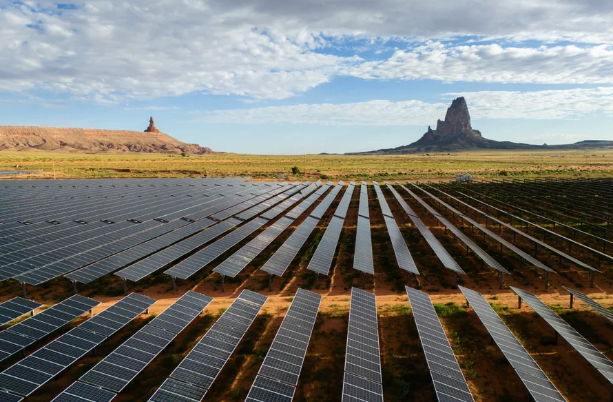 A large solar array, with geologic outcroppings in the background