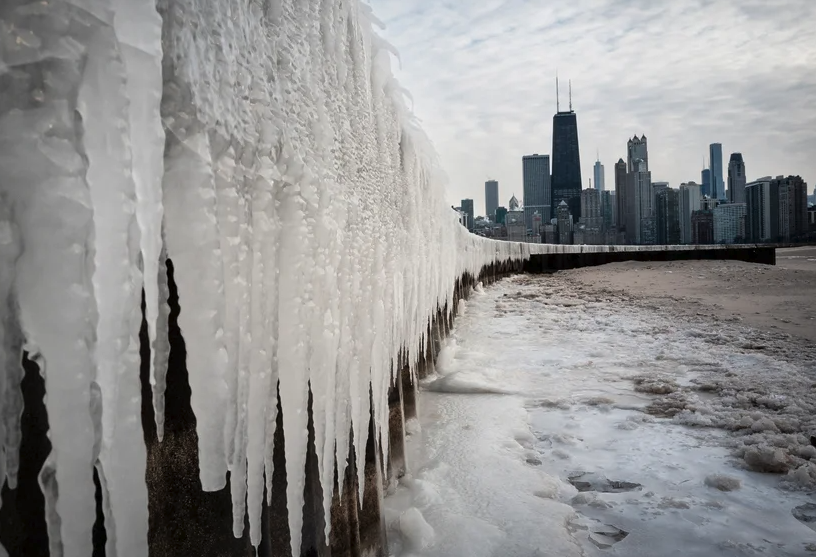 Icicles collect on the shore of Lake Michigan, with the city skyline of Chicago in the background.