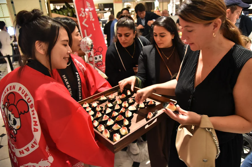 A customer tries peaches from Japan's Fukushima prefecture at the luxury department store Harrods in central London.