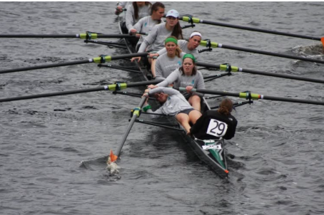 Image of an eight-oared rowing shell rowing along. Stroke seat's blade is stuck in the water and their handle is back behind their head.