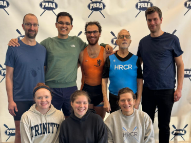 Eight people pose in front of a background that has the PRRA logo.