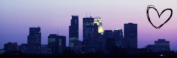 A view of downtown Minneapolis, Minnesota at dusk, viewed from the East, with an outline of a heart on the right.