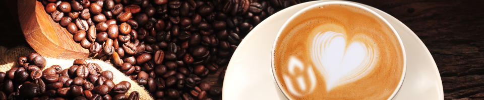 Coffee beans spill out of a burlap sack next to a latte with a foam heart and UUA chalice in a white mug on a saucer.