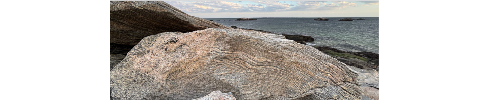 The rocky Connecticut coastline with cloudy skies and the ocean in the distance.