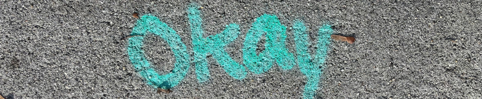 Okay is written in blue spray paint on concrete.