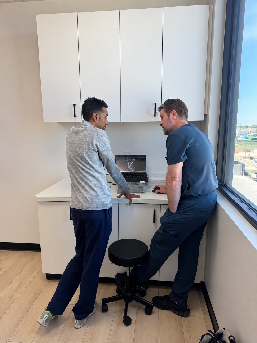 Two people reviewing spine imaging on a laptop